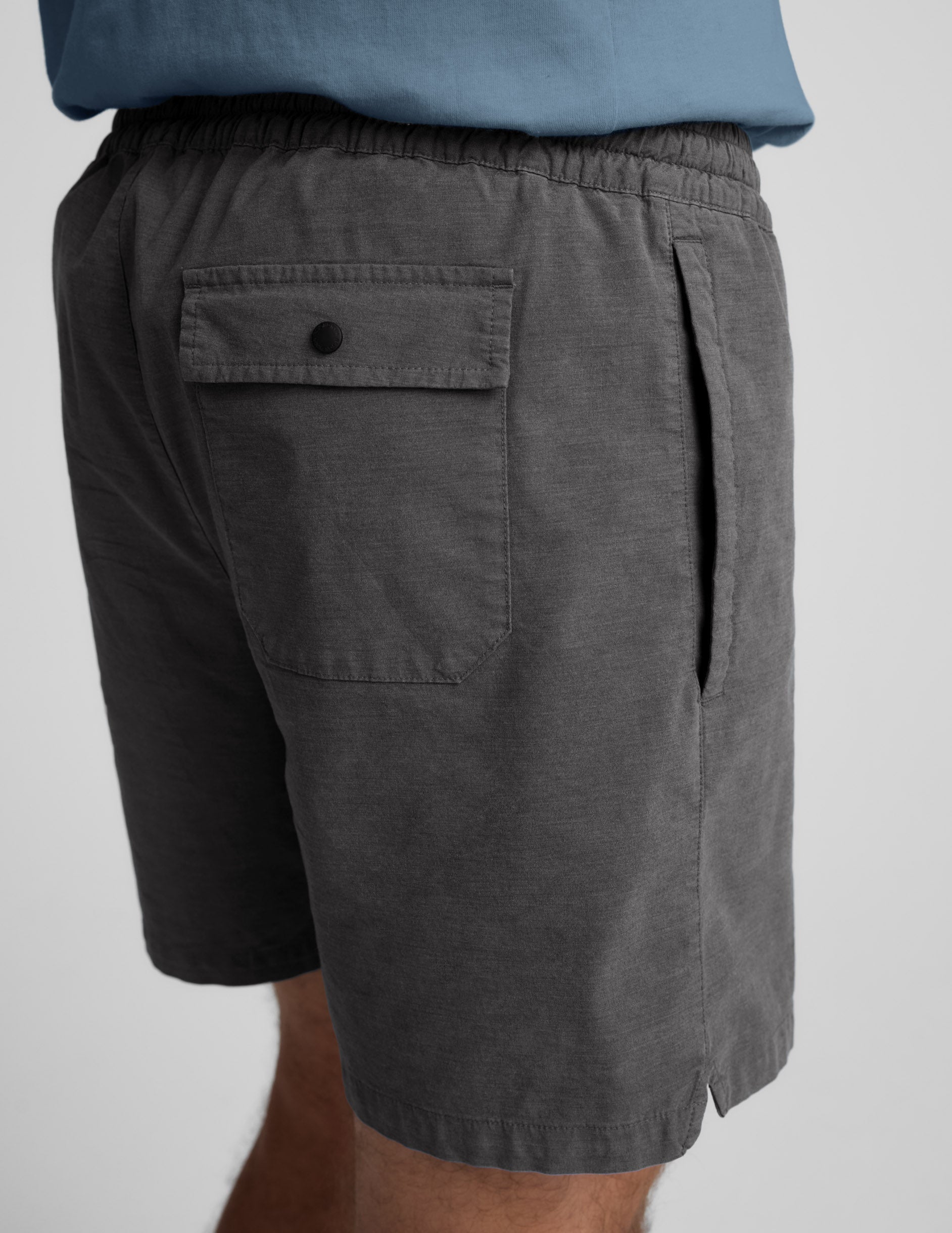Back view of gray Saturday Men's Short with elastic waist, side pocket, and a back patch pocket with a snap closure.