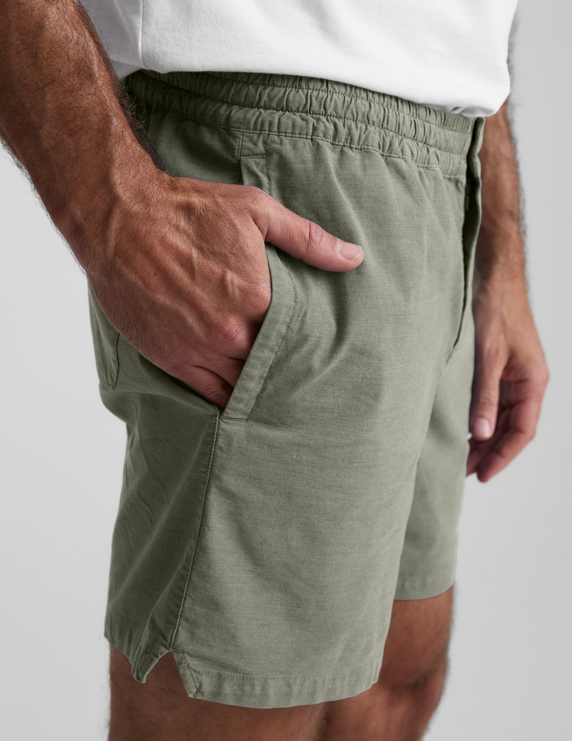 Side profile of olive Saturday Men's Short showing the elastic waistband, side pocket, and soft peached finish on a model.