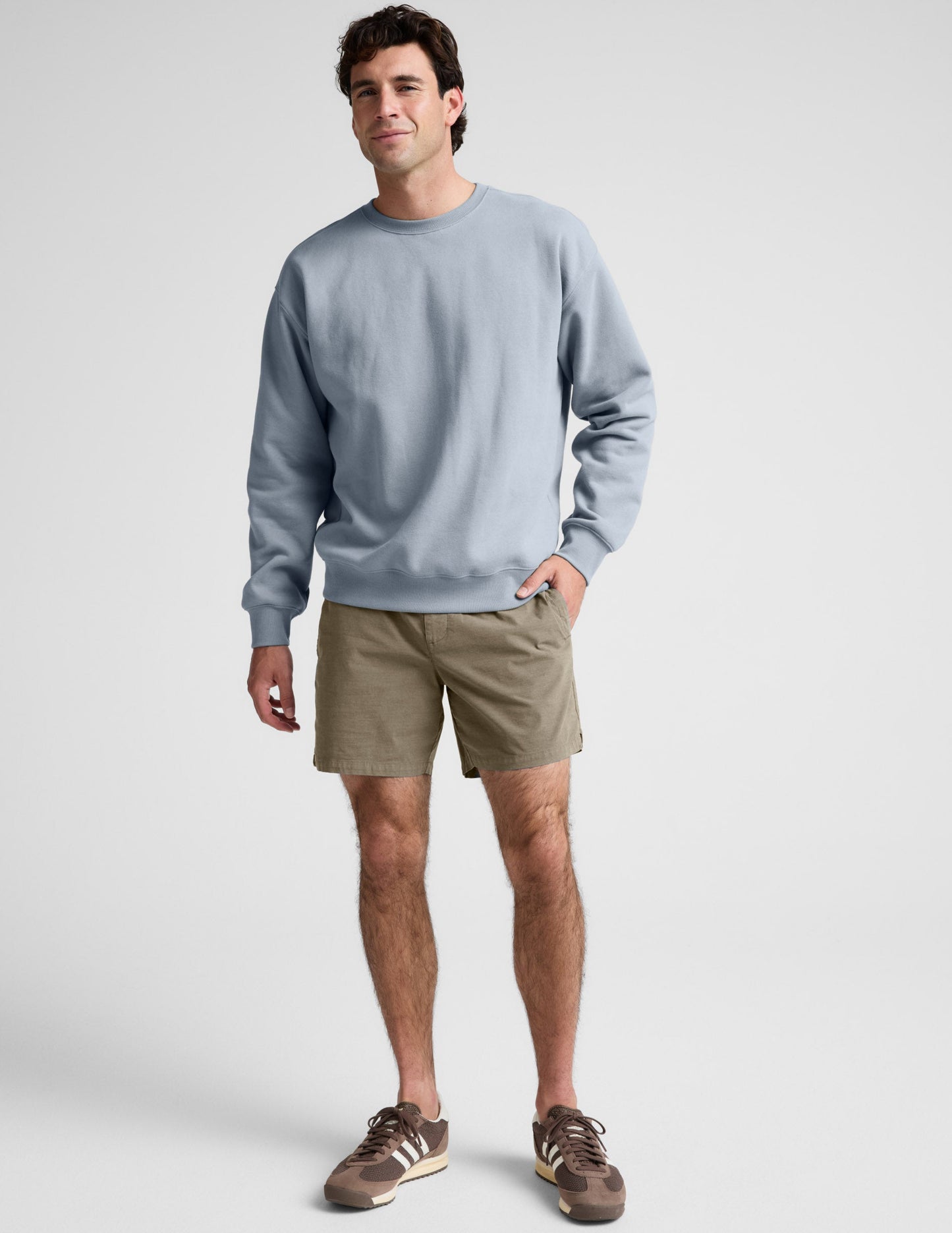 Saturday Men's Short in Olive green, featuring an elastic waist and mid-thigh length, worn by a model with a sweatshirt.