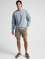 Saturday Men's Short in Olive green, featuring an elastic waist and mid-thigh length, worn by a model with a sweatshirt.