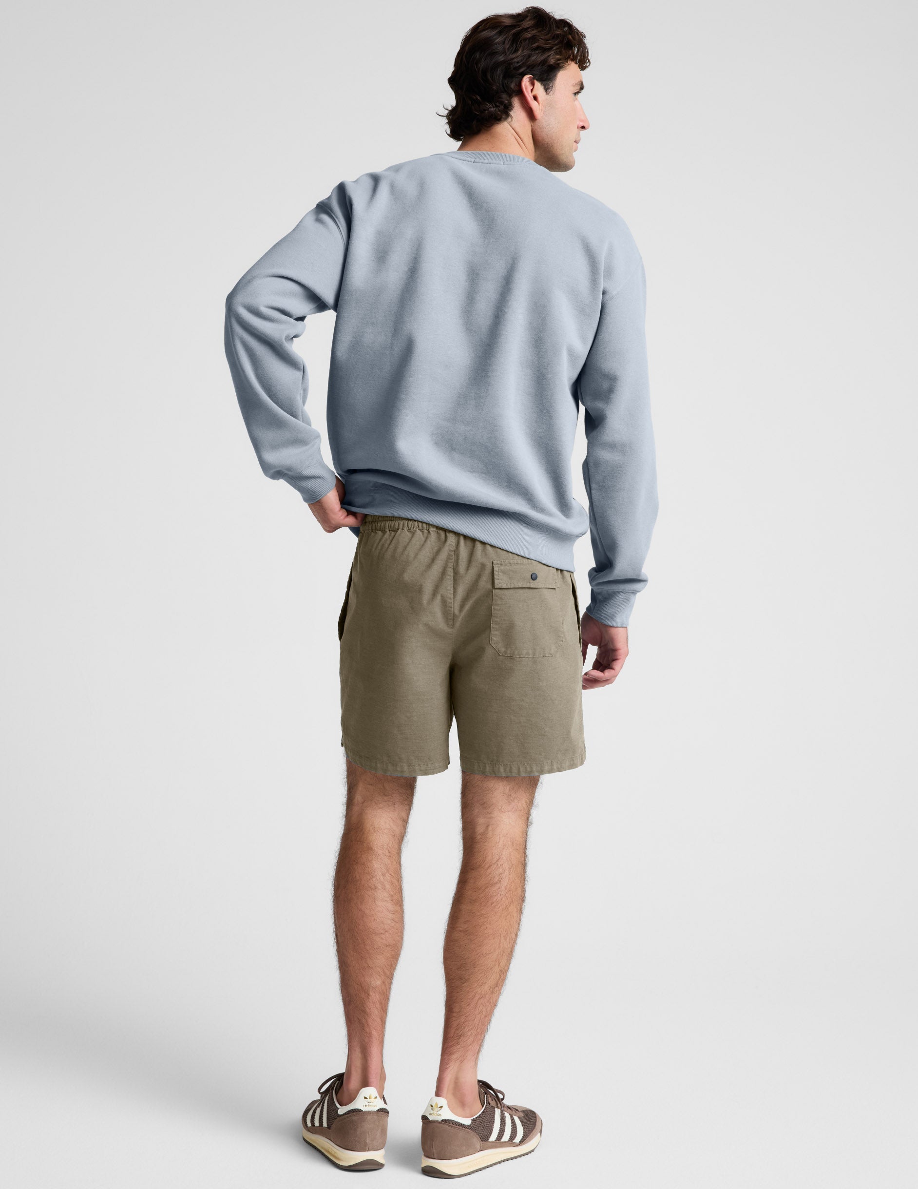 Rear view of the olive Saturday Men's Short showing the elasticated waistband and back patch pocket with a snap button.