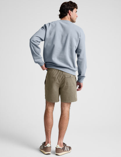 Rear view of the olive Saturday Men's Short showing the elasticated waistband and back patch pocket with a snap button.