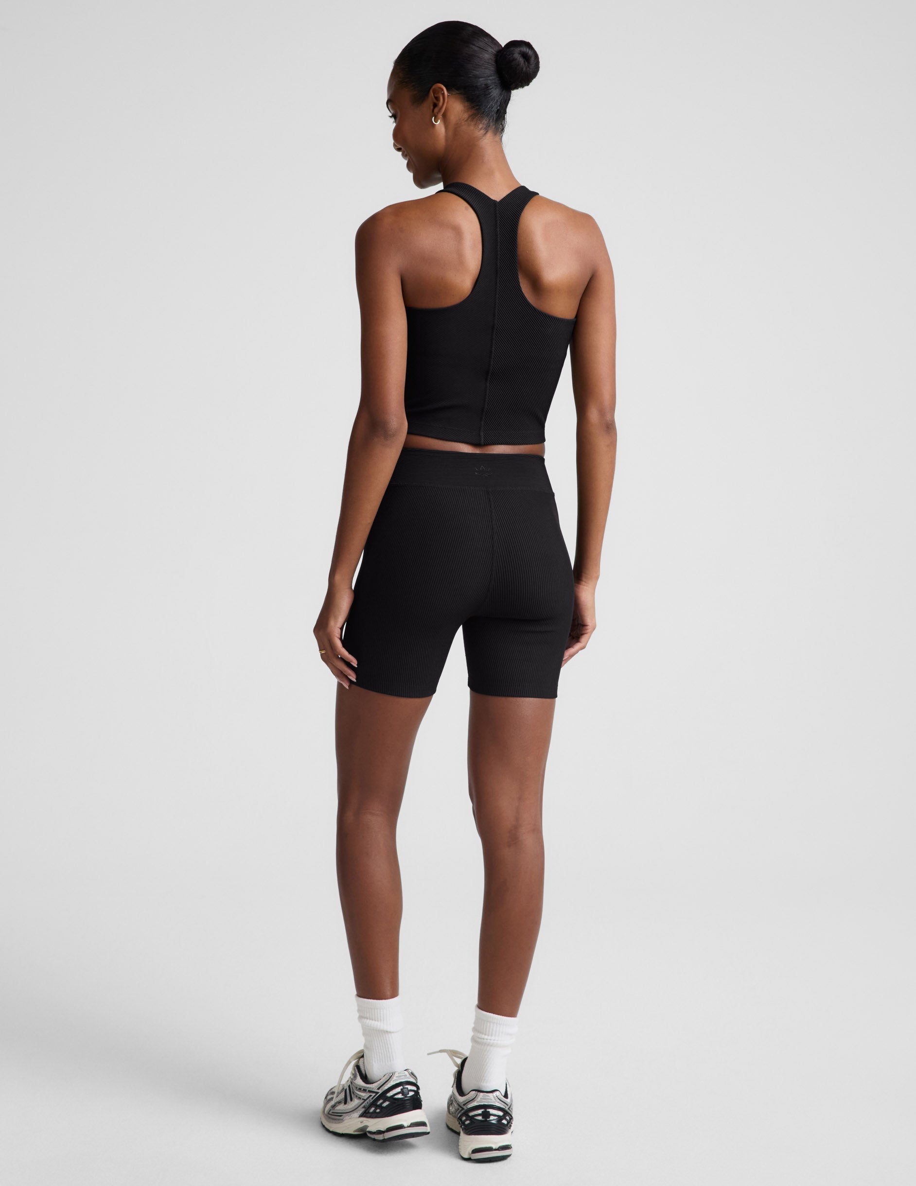 Woman wearing Black Impulse Ribbed V-Waist 5" Biker Short™ paired with a black racerback tank top, rear view.