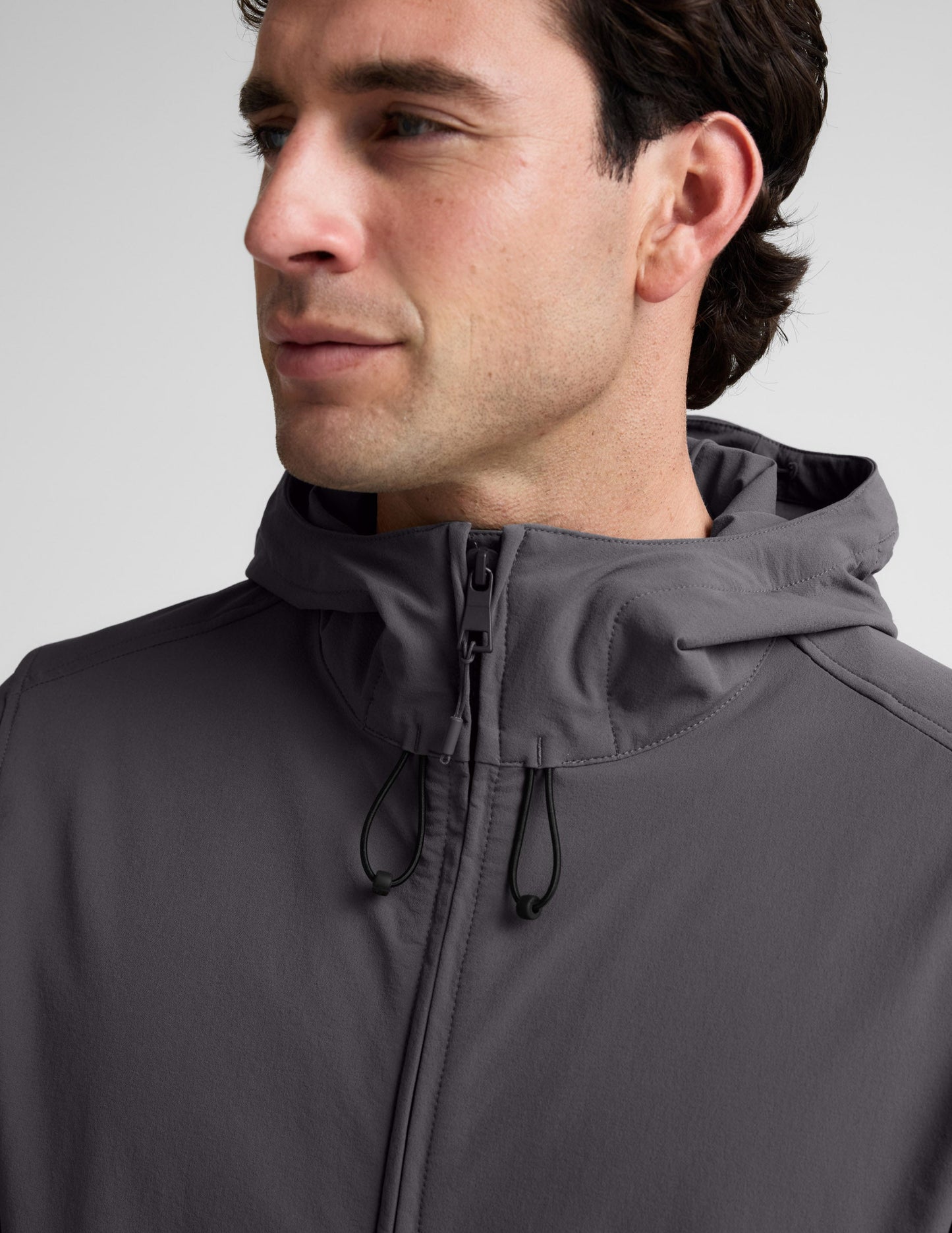 Man wearing a gray hooded jacket on a light gray background.