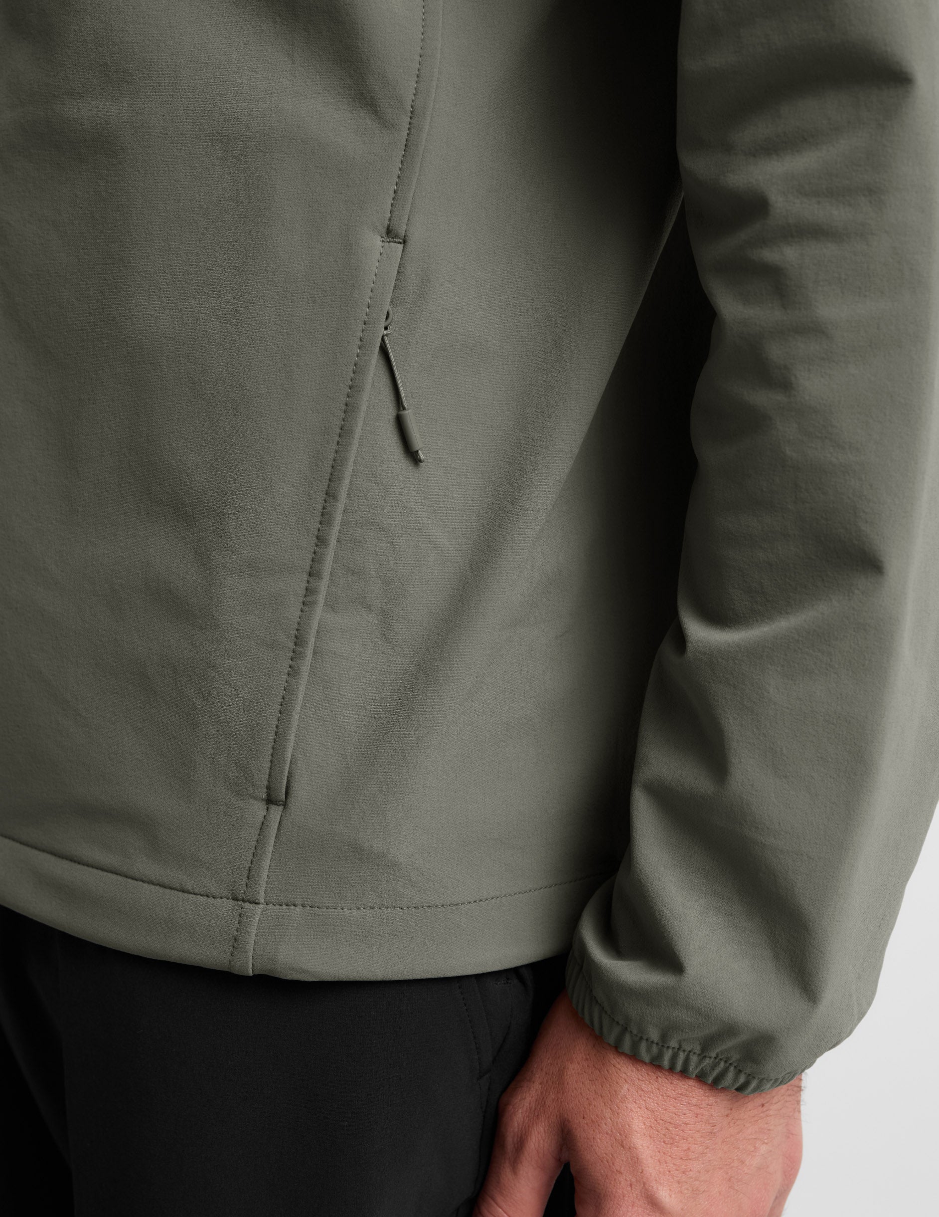 Man wearing a green jacket and black pants on a plain background.