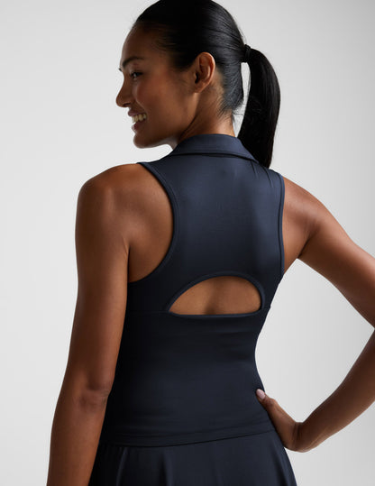 Woman wearing a blue sleeveless top with a collar against a plain background.