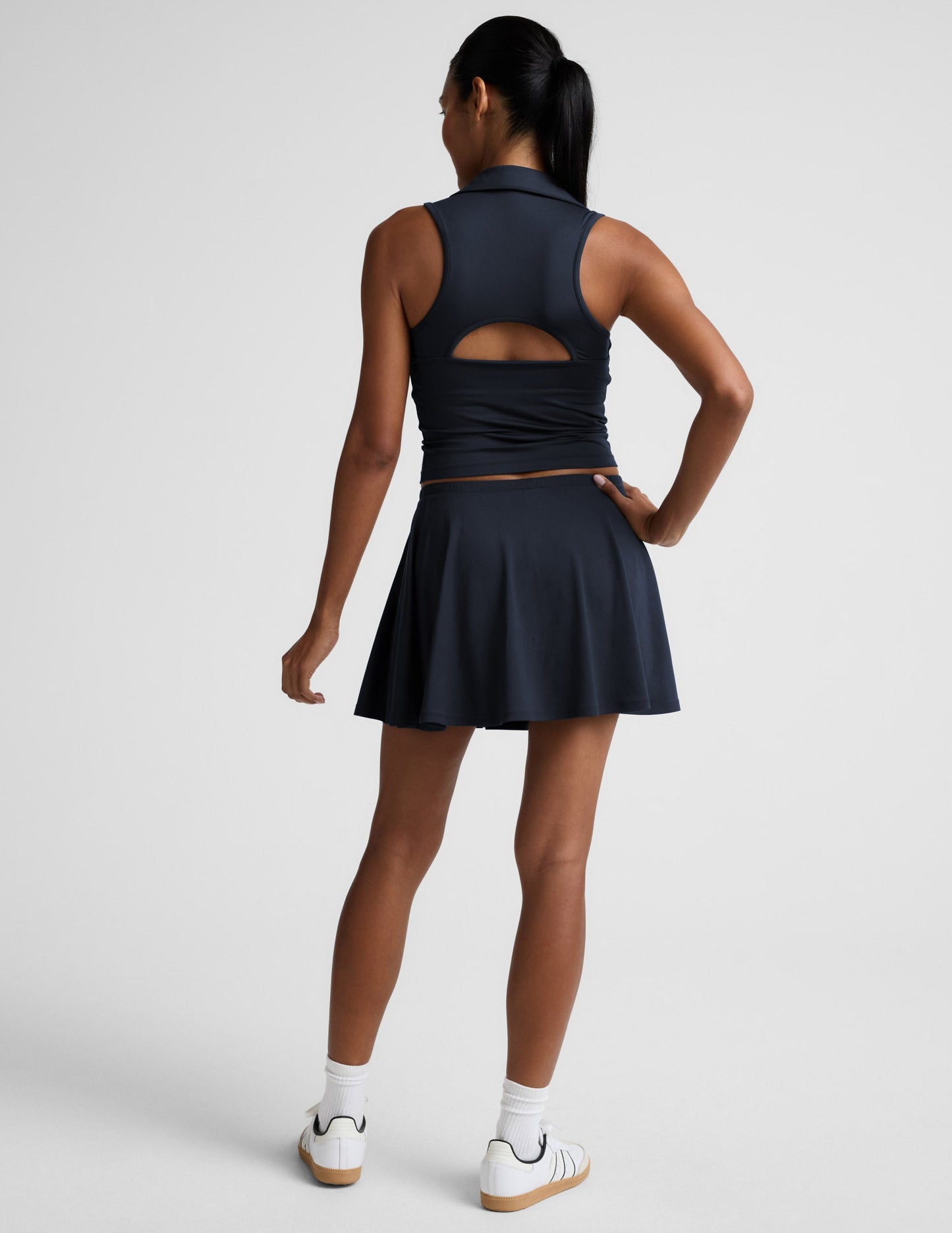 Back view of the navy Sport Active Drawcord Mini Skirt, a relaxed A-line tennis skirt styled with white socks and sneakers.