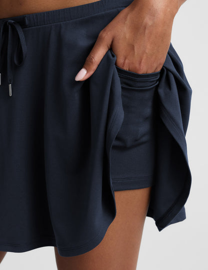 Close-up of Navy Sport Active Drawcord Mini Skirt showing a hand using the pocket in the built-in shorts.