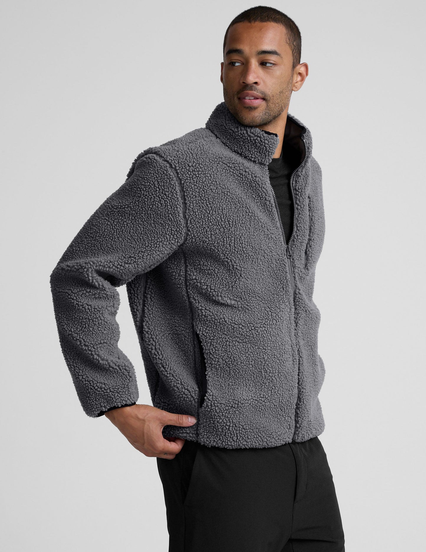 man wearing a gray fleece zip-up jacket against a plain background.