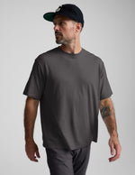 Man wearing a black cotton tee and pants against a plain background.