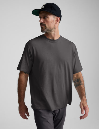 Man wearing a black cotton tee and pants against a plain background.