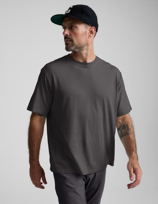 Man wearing a black cotton tee and pants against a plain background.