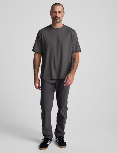Man wearing a black cotton tee and pants against a plain background.