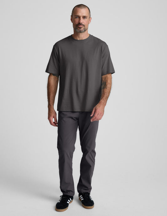 Man wearing a black cotton tee and pants against a plain background.