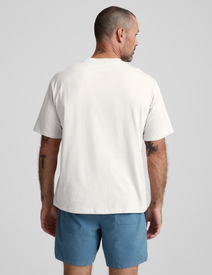 Man wearing a white cotton t-shirt and blue shorts on a light gray background.