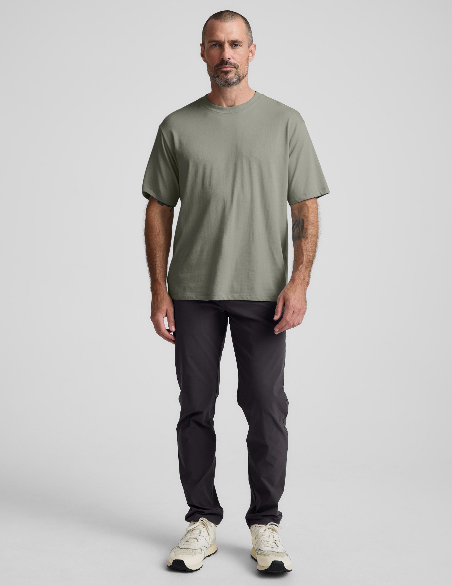 Man wearing a green cotton t-shirt and black pants against a plain background.