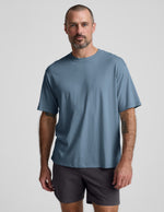 Man wearing a blue cotton t-shirt and gray shorts against a plain background.