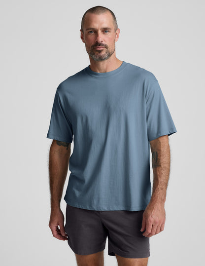 Man wearing a blue cotton t-shirt and gray shorts against a plain background.