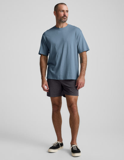 Man wearing a blue cotton t-shirt and gray shorts against a plain background.