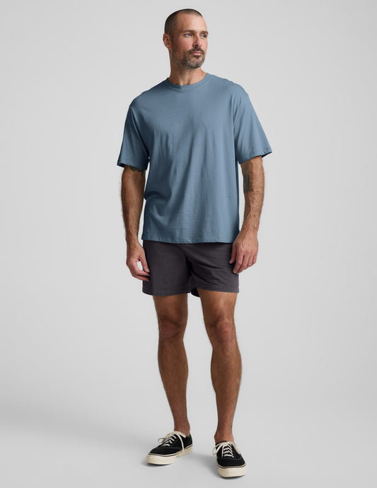 Man wearing a blue cotton t-shirt and gray shorts against a plain background.