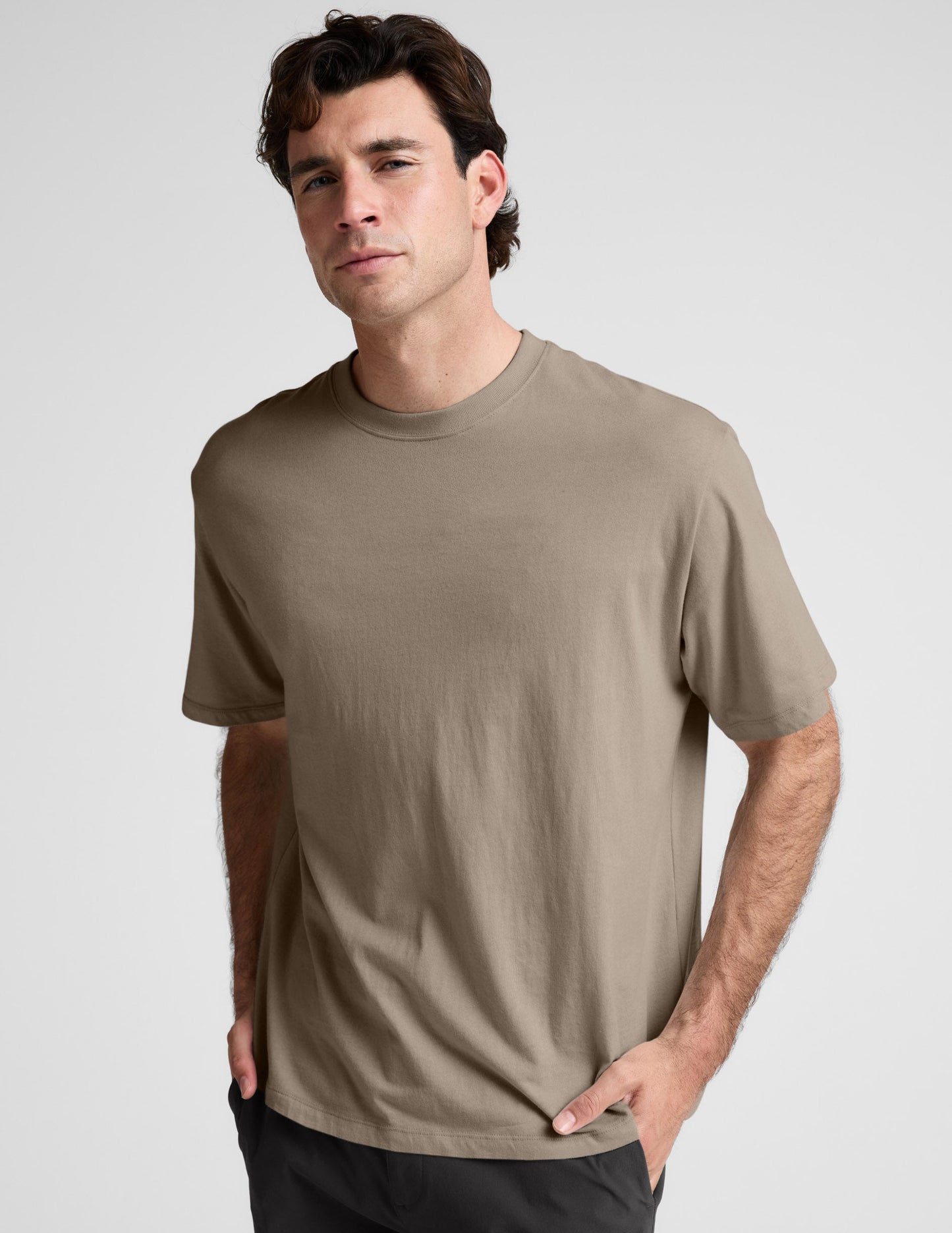 Man wearing a plain brown t-shirt against a light gray background.