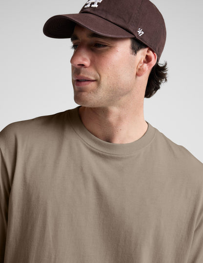 Man wearing a plain brown t-shirt against a light gray background