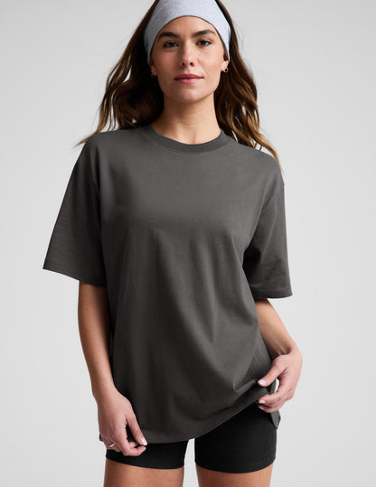 Woman wearing a dark gray t-shirt and black biker shorts against a plain background.