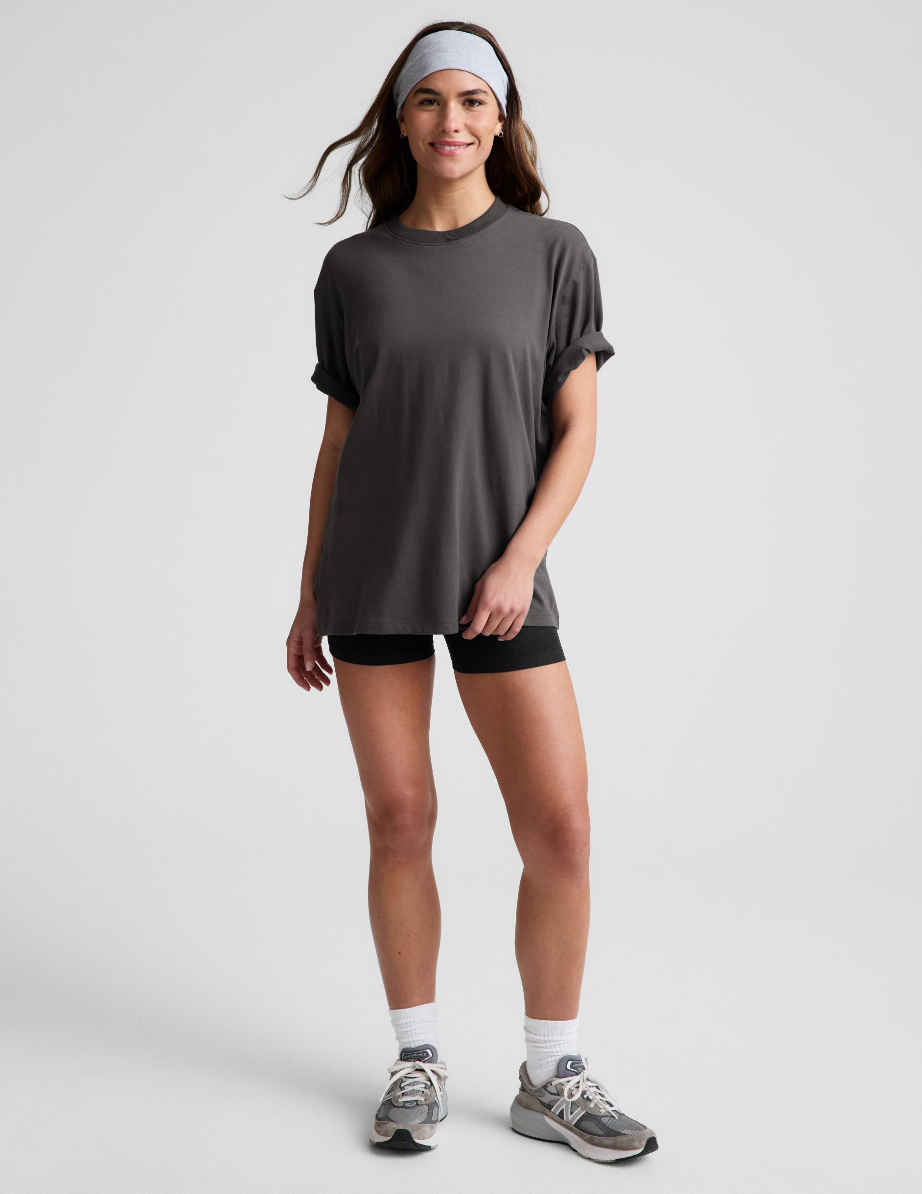 Woman wearing a dark gray t-shirt and black biker shorts against a plain background.