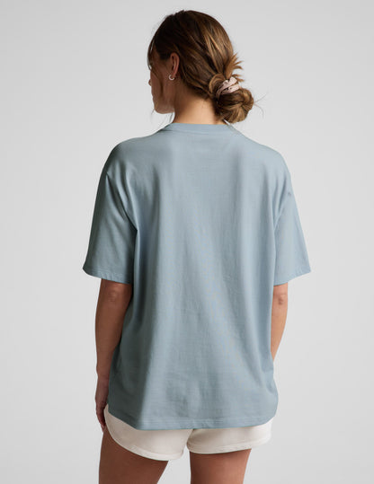 Woman wearing a blue t-shirt and white shorts against a plain background.