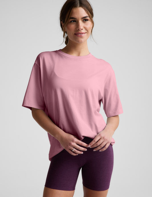 Woman wearing a pink t-shirt and purple shorts against a plain background.