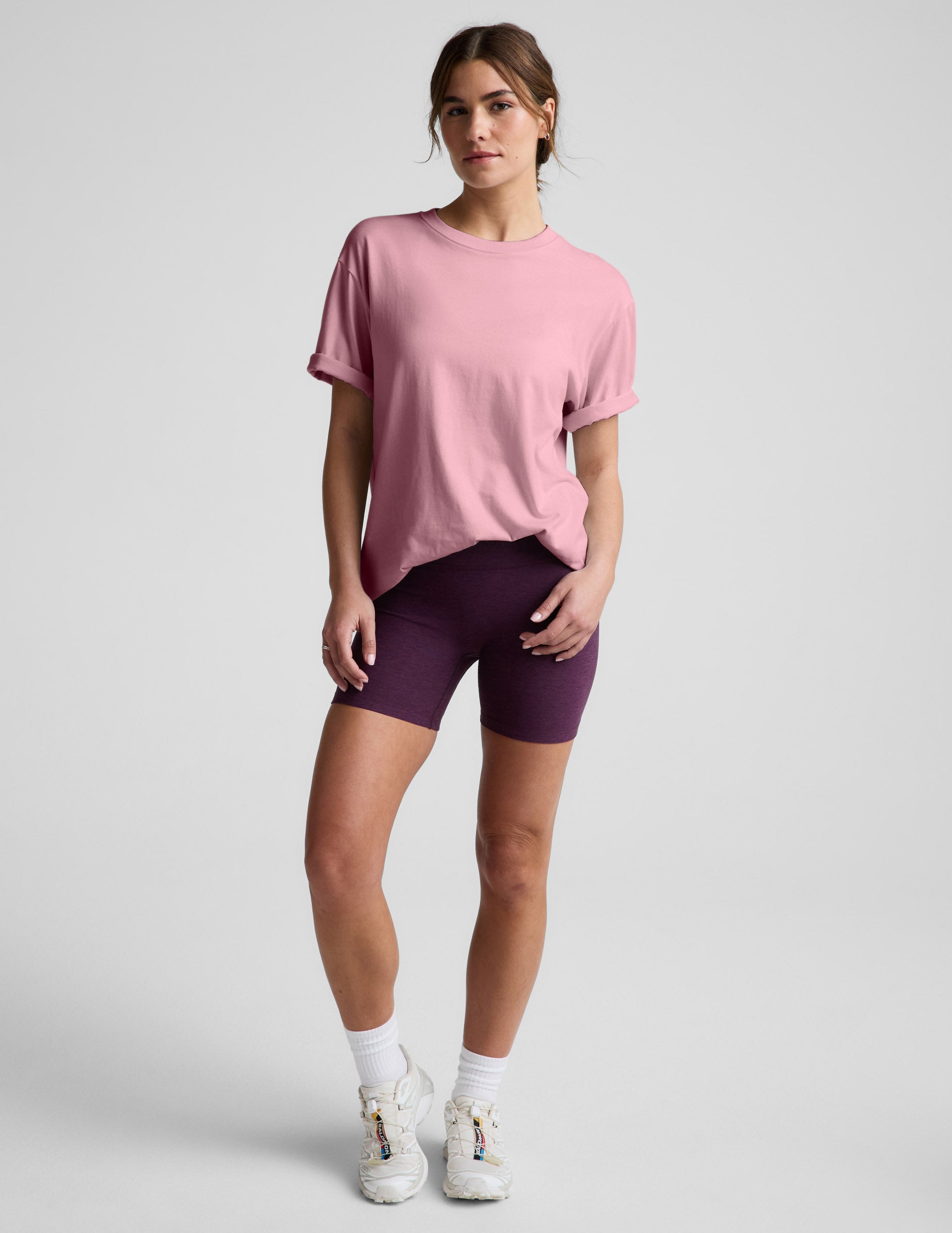 Woman wearing a pink t-shirt and purple shorts against a plain background.
