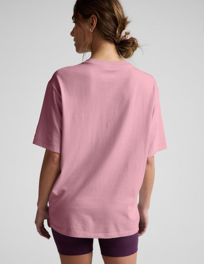Woman wearing a pink t-shirt and purple shorts against a plain background.