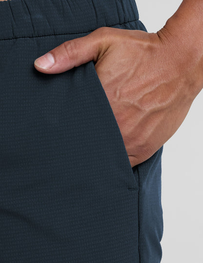 Close-up of navy Dynamic Men's Straight Leg Pant showing a hand in the side pocket and the elastic waistband's texture.