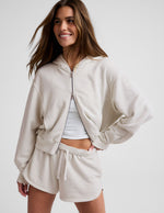 Woman wearing a white sweatshirt and shorts on a plain background.