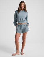 Model wearing Capri Blue Fade Out Mid-Rise Shorts with drawstring and curved hem, paired with matching cropped hoodie.