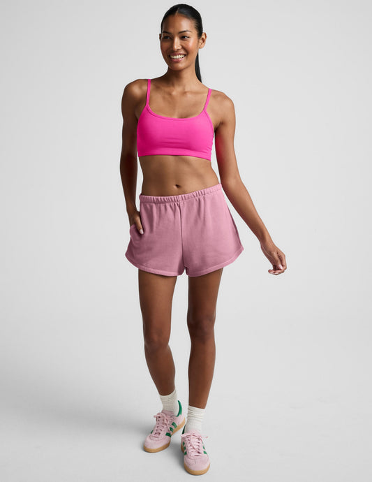 Smiling model wearing pink Fade Out Mid-Rise Short with curved hems and side pockets against a neutral studio background.