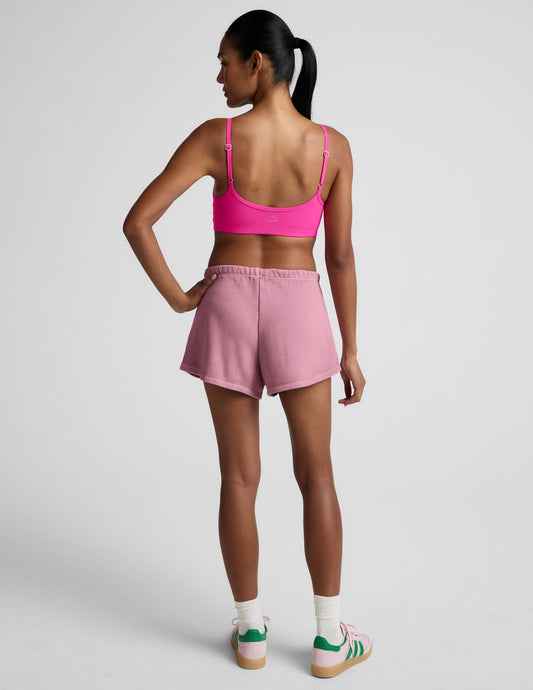 Rear view of a model wearing the pink Fade Out Mid-Rise Short, featuring a curved hem and soft elastic waistband.