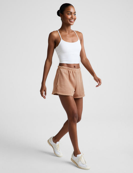 Woman wearing Cream Fade Out Mid-Rise Short with a white tank top and sneakers, featuring a gathered elastic waistband.