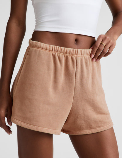 Woman wearing Cream Fade Out Mid-Rise Short™ with a gathered elastic waistband, paired with a white cropped tank top.