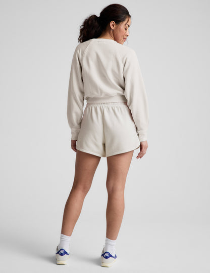 Rear view of model in cream Fade Out Mid-Rise Short featuring a curved dolphin hem and gathered elastic waistband.