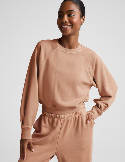 Woman wearing a beige sweatshirt and pants set on a plain background.