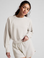 Woman wearing a white crew-neck and shorts against a plain background.