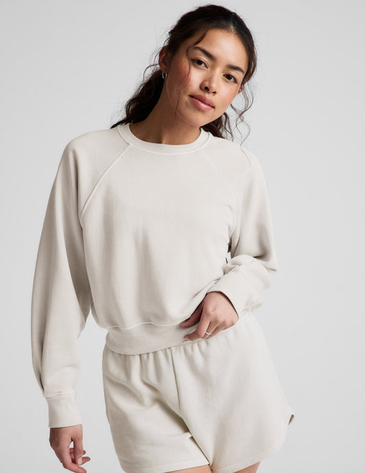 Woman wearing a white crew-neck and shorts against a plain background.