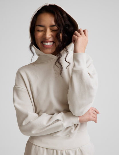 Woman wearing a white hoodie and pants against a plain background.