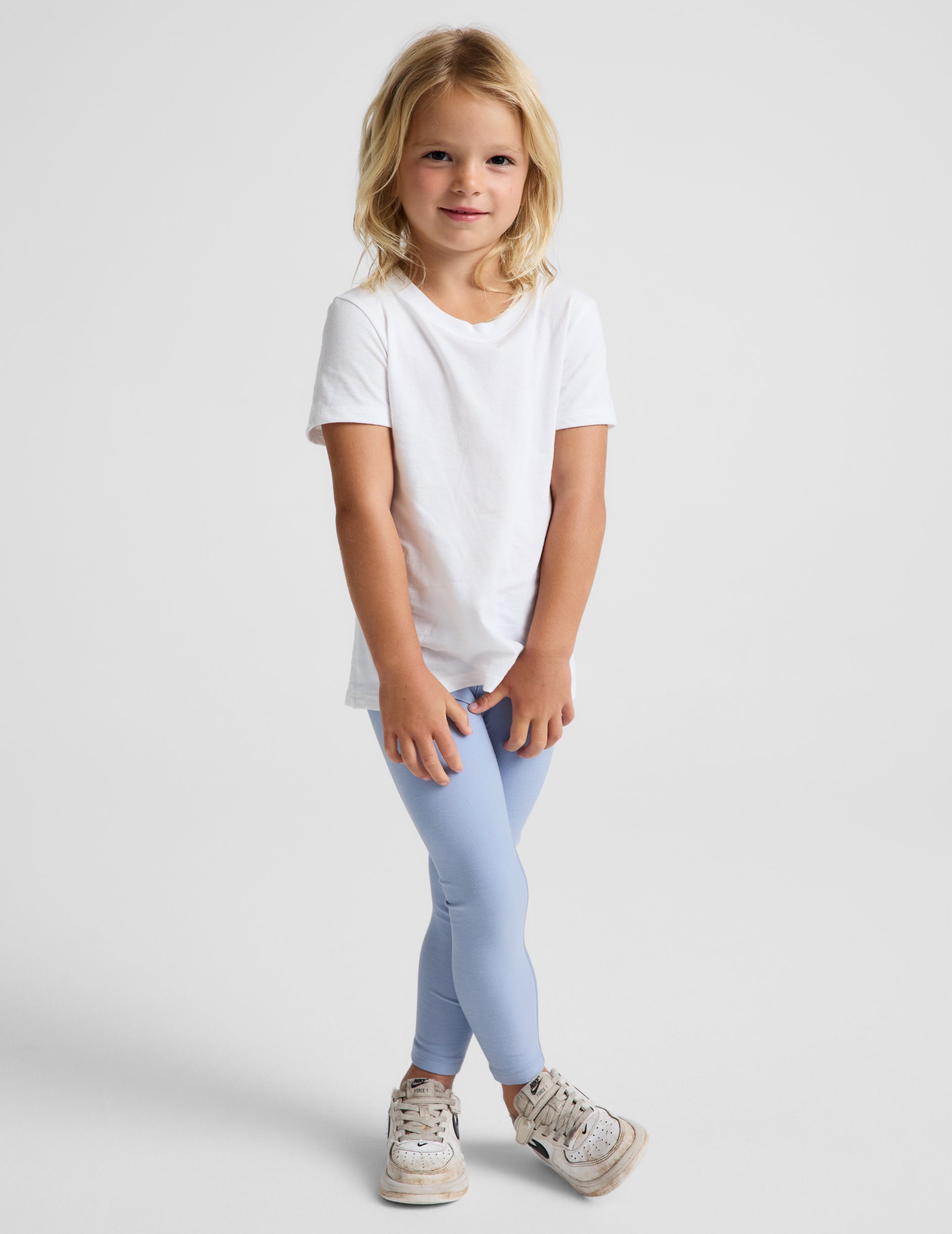 Girl wearing Blue Spacedye™ Toddler Legging with a white t-shirt and sneakers.