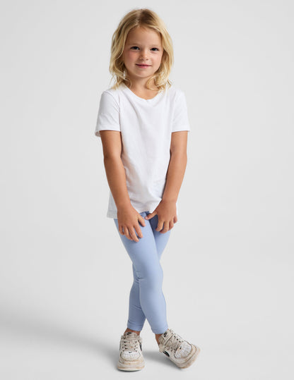 Girl wearing Blue Spacedye™ Toddler Legging with a white t-shirt and sneakers.