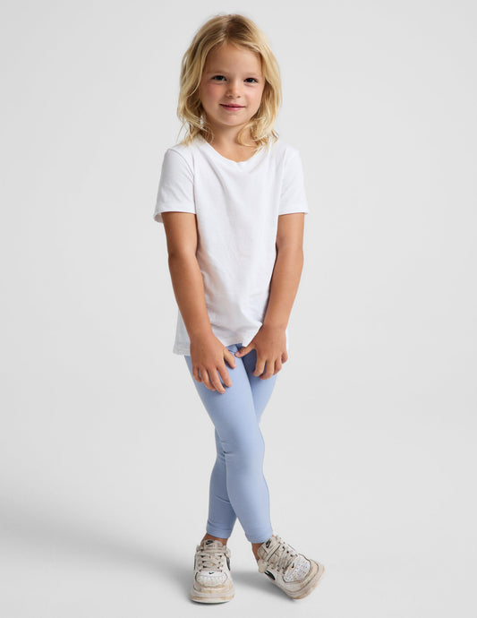 Girl wearing Blue Spacedye™ Toddler Legging with a white t-shirt and sneakers.