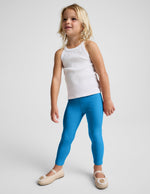 Girl wearing Blue Spacedye™ Toddler Legging paired with a white ribbed tank top and tan ballet flats.