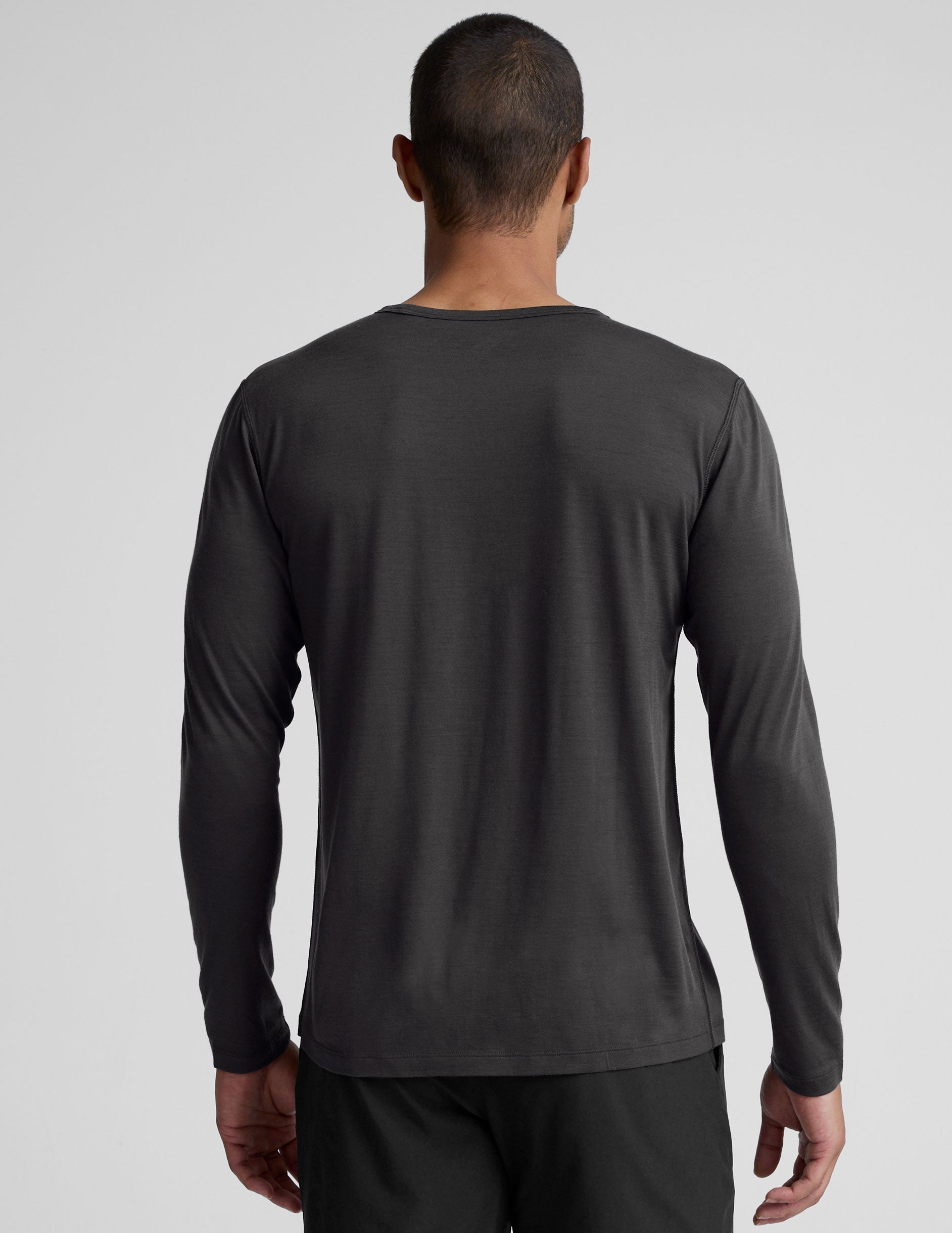 man wearing a black long-sleeve shirt against a plain background.