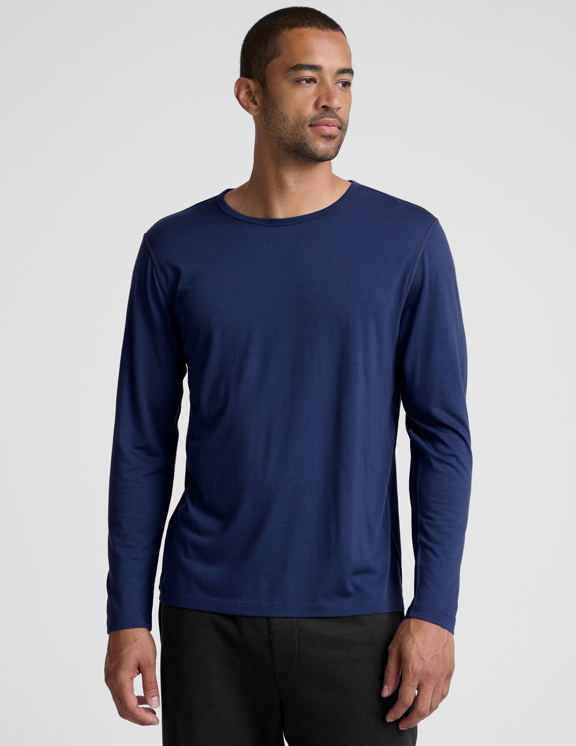 man wearing a blue long-sleeve shirt against a plain background.